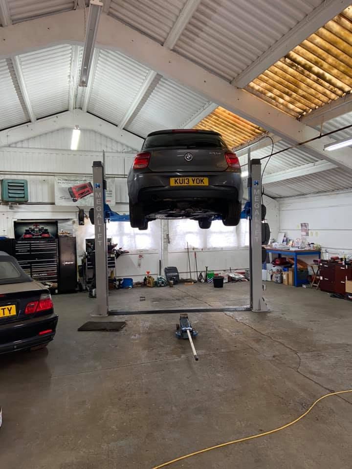Inside the workshop, a BMW raised on the two-post lift